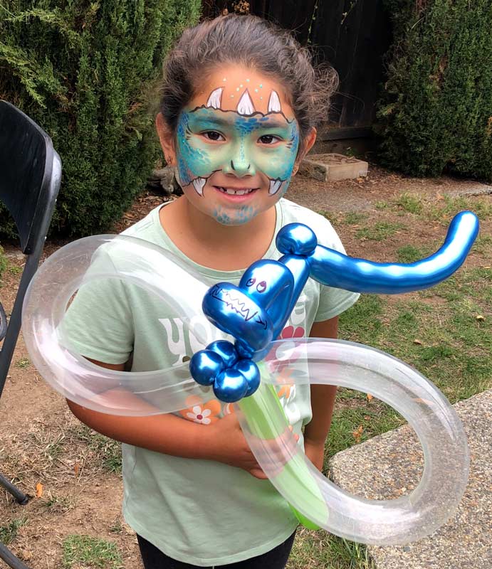 girl with green dragon face paint holding dragon balloon. By Auntie Stacey's Face Painting and Balloon Twisting